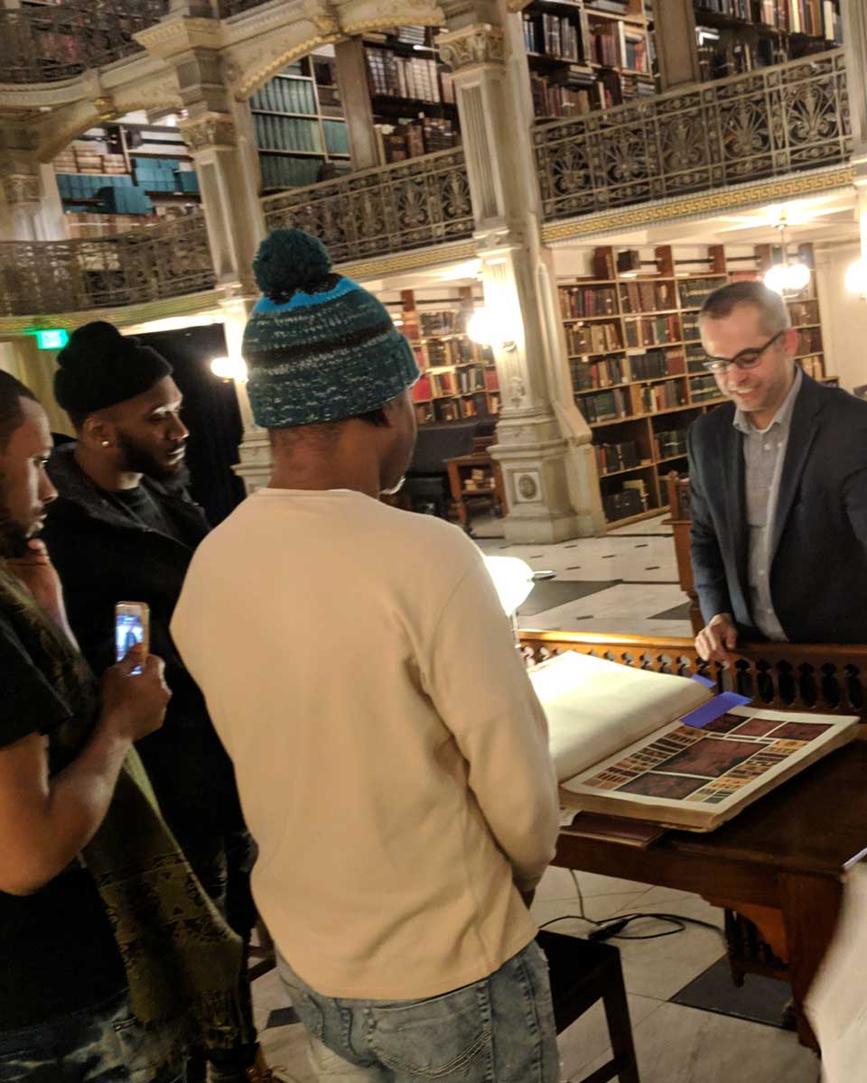 a person in a suit shows a book to a group of people